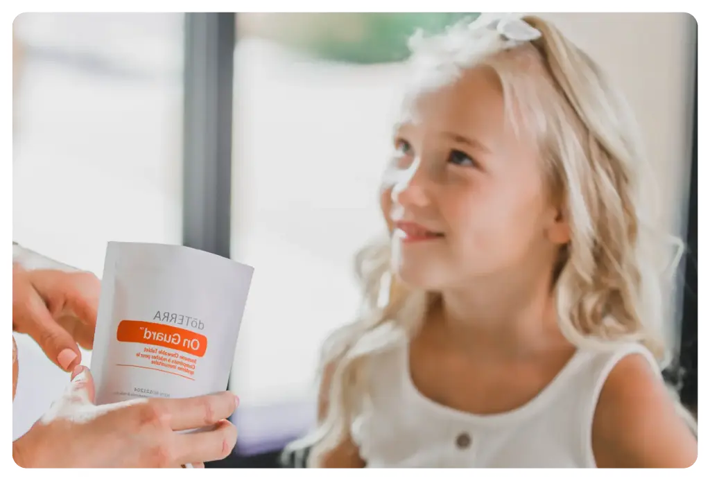 Kisgyermek mosolyog, miközben egy felnőtt kéz egy illóolajos terméket tart elé otthoni környezetben.